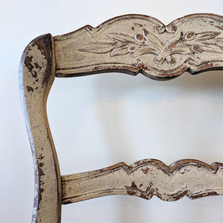 An old wooden chair with wearing white paint