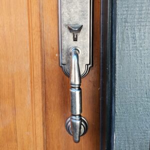 A polished iron door handle on a wooden front door