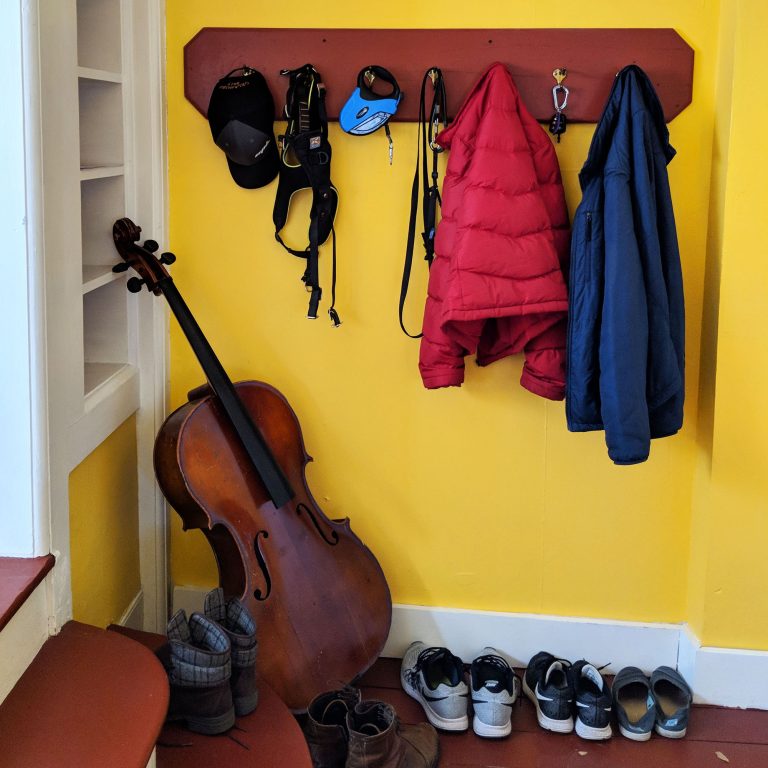 yellow entry way with coat rack and cello