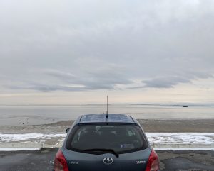 blue hatchback in front of cold atlantic ocean