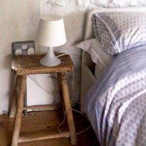 small milkstool serving as a nightstand
