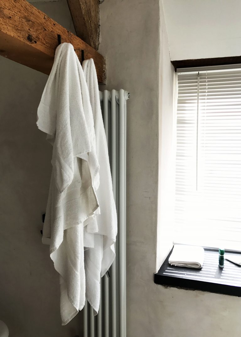 two white towels hanging from exposed wooden bean
