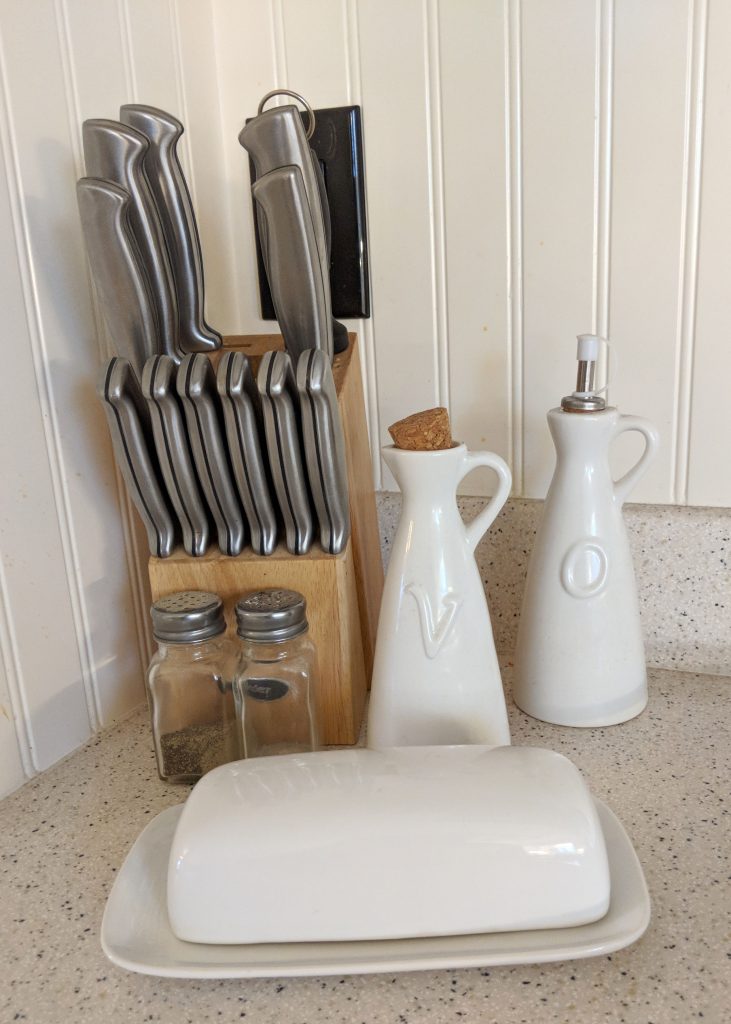 a knife block, butter container, and vinegar and olive oil pitchers