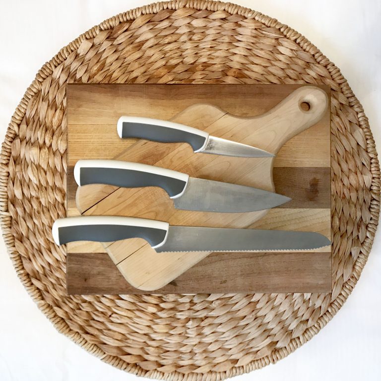 a pairing knife, chef's knife, and serrated knife on a cutting board