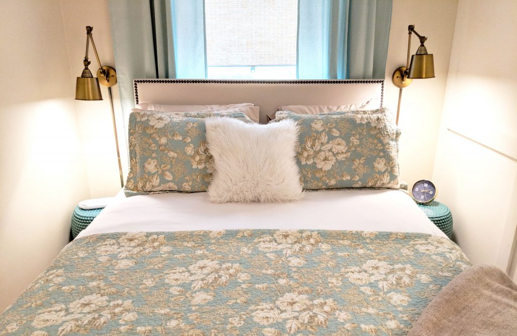 bed with teal quilt and many pillows