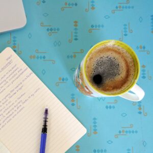 cup of coffee and notebook on teal table in Airbnb in Saskatoon