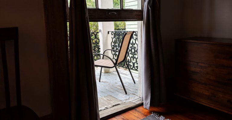 chair through curtains on porch in New Orleans Airbnb